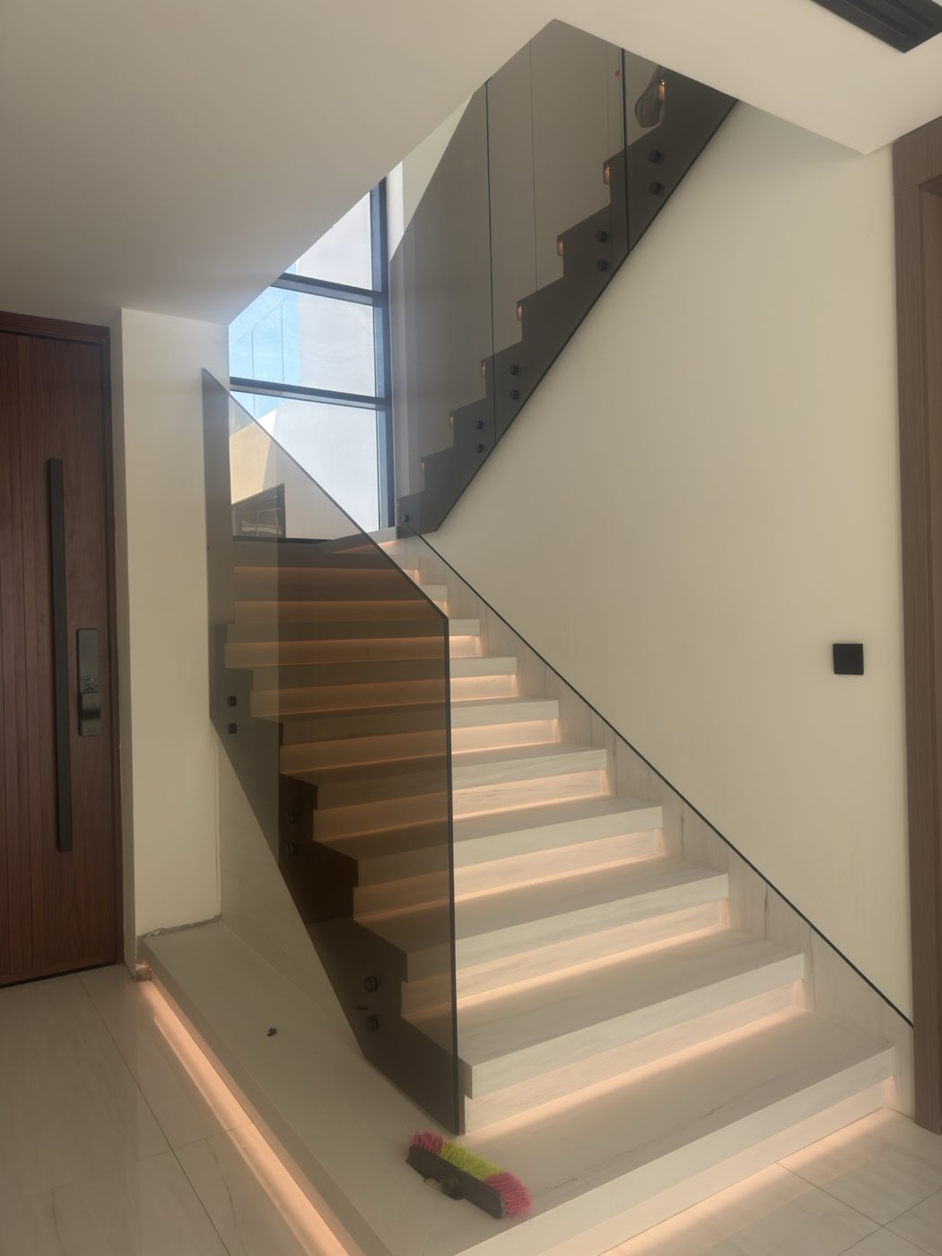 Smoked glass staircase balustrade with stud fixings and step lighting