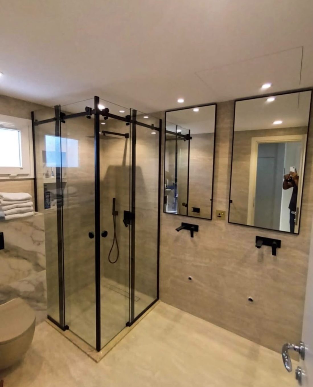 Black-framed sliding shower glass enclosure with matching mirrors in a Dubai bathroom